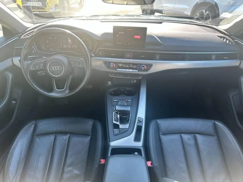 Vue intérieure avant de l'Audi A5 Sportback 2018 avec tableau de bord noir, volant cuir multifonction et console centrale argentée.