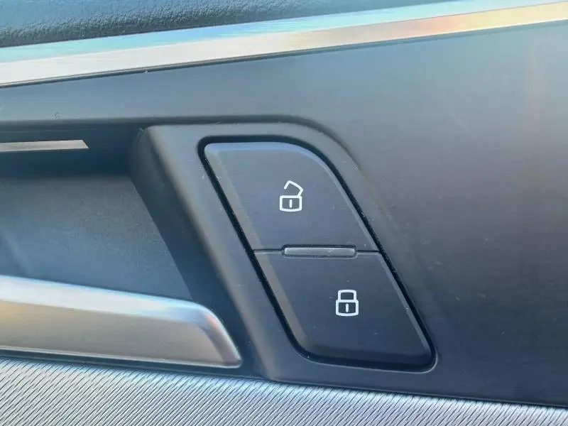 Gros plan sur les boutons de verrouillage centralisé noir sur la porte intérieure d’une Audi A5 Sportback grise.