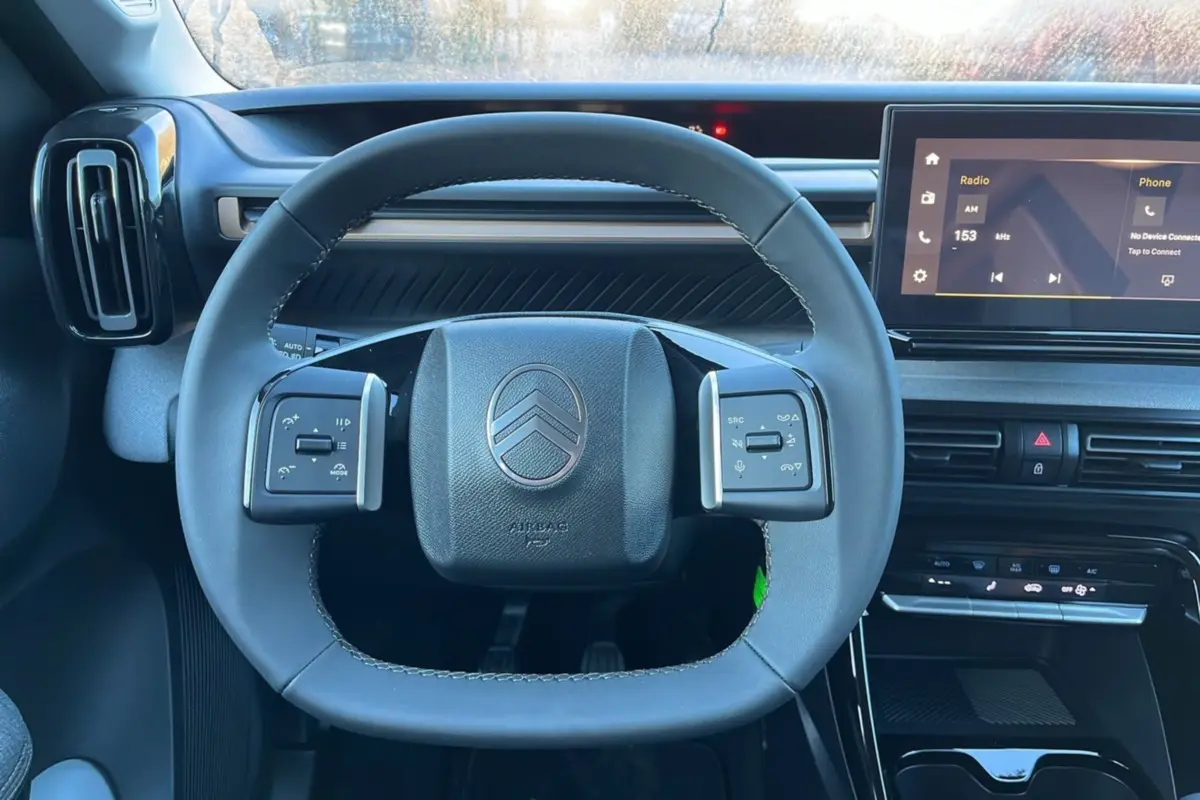 Vue intérieure centrée sur le volant cuir multifonctions et l'écran tactile du tableau de bord du Citroën C3 Aircross 2025.
