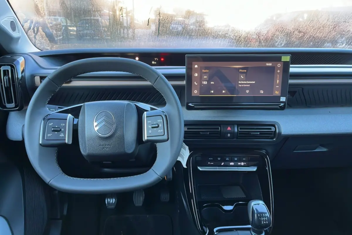Vue intérieure centrée sur le volant cuir multifonctions et l’écran tactile 10,25 pouces du Citroën C3 Aircross noir.