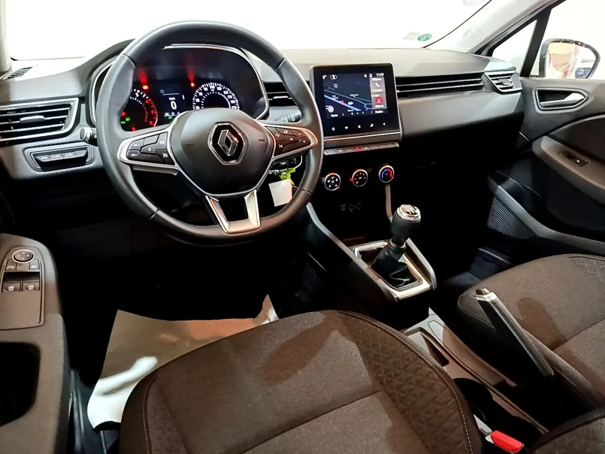 Vue intérieure côté conducteur de la Renault Clio Business 2021, volant cuir, écran tactile et levier de vitesses manuel visibles.