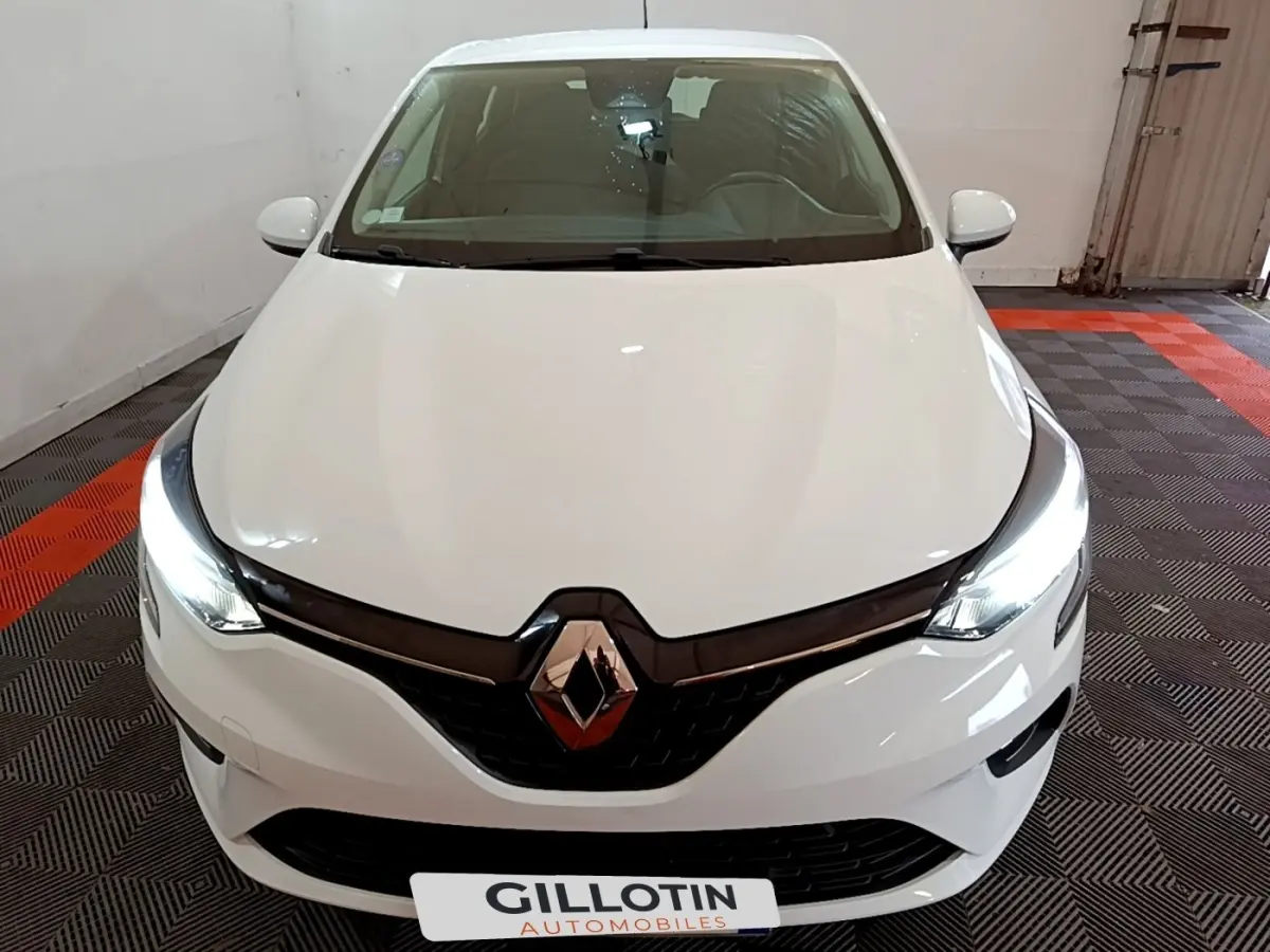 Vue avant d'une Renault Clio Business blanche avec phares LED allumés dans un garage fermé.