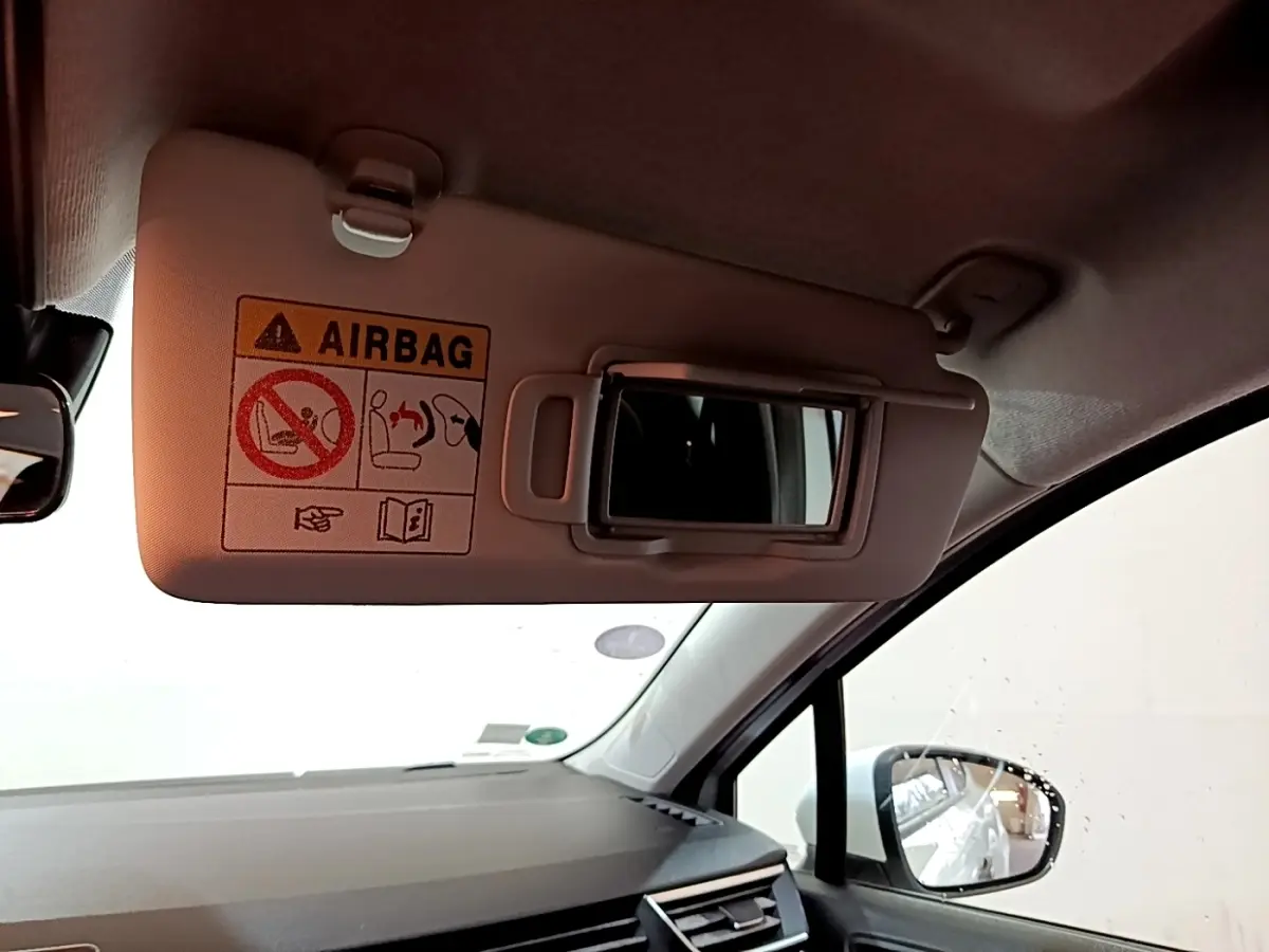 Détail du pare-soleil côté conducteur avec miroir et avertissement airbag dans l'habitacle d'une Renault Clio blanche.