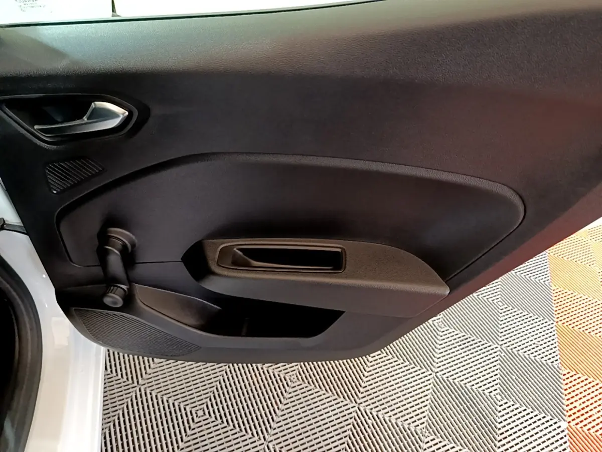 Vue rapprochée de la porte avant gauche noire d’une Renault Clio Business blanche, avec poignée intérieure et manivelle de vitre.