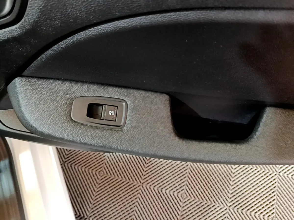 Gros plan sur la commande de verrouillage de porte côté intérieur d’une Renault Clio Business blanche, 2021.