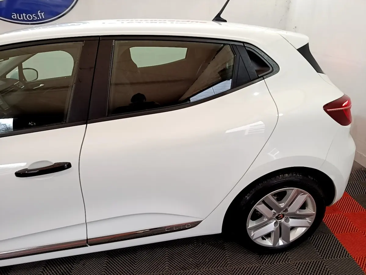 Vue latérale côté gauche d'une Renault Clio blanche avec jantes alliage et poignées de porte noires.