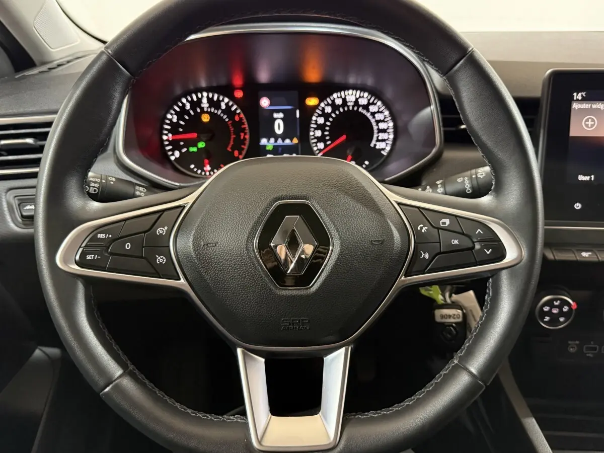 Vue rapprochée du volant cuir noir de la Renault Clio Business 2020 avec tableau de bord et commandes intégrées.