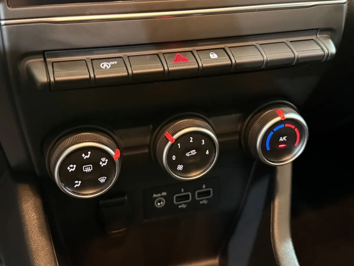 Gros plan sur les commandes de climatisation et boutons de fonction du tableau de bord de la Renault Clio Business blanche de 2020.