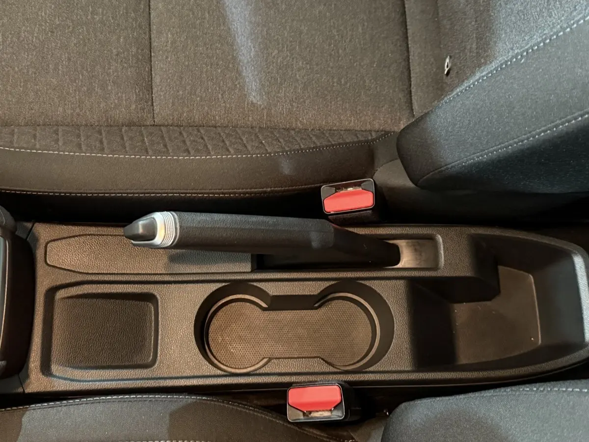 Gros plan sur la console centrale noire de la Renault Clio Business 2020, avec frein à main manuel et porte-gobelets.