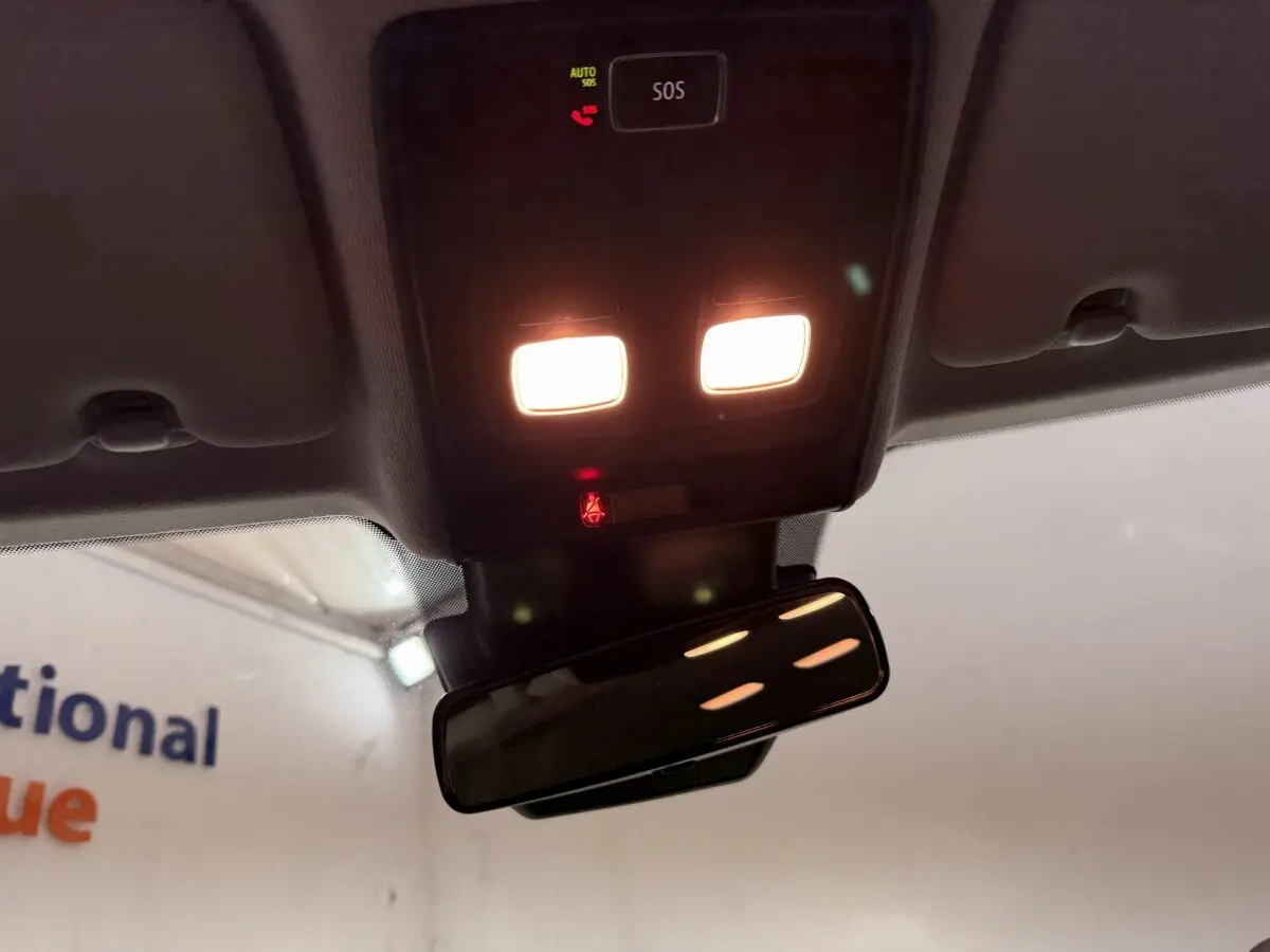 Vue intérieure en plongée du plafonnier allumé avec bouton SOS et rétroviseur intérieur d'une Renault Clio blanche.