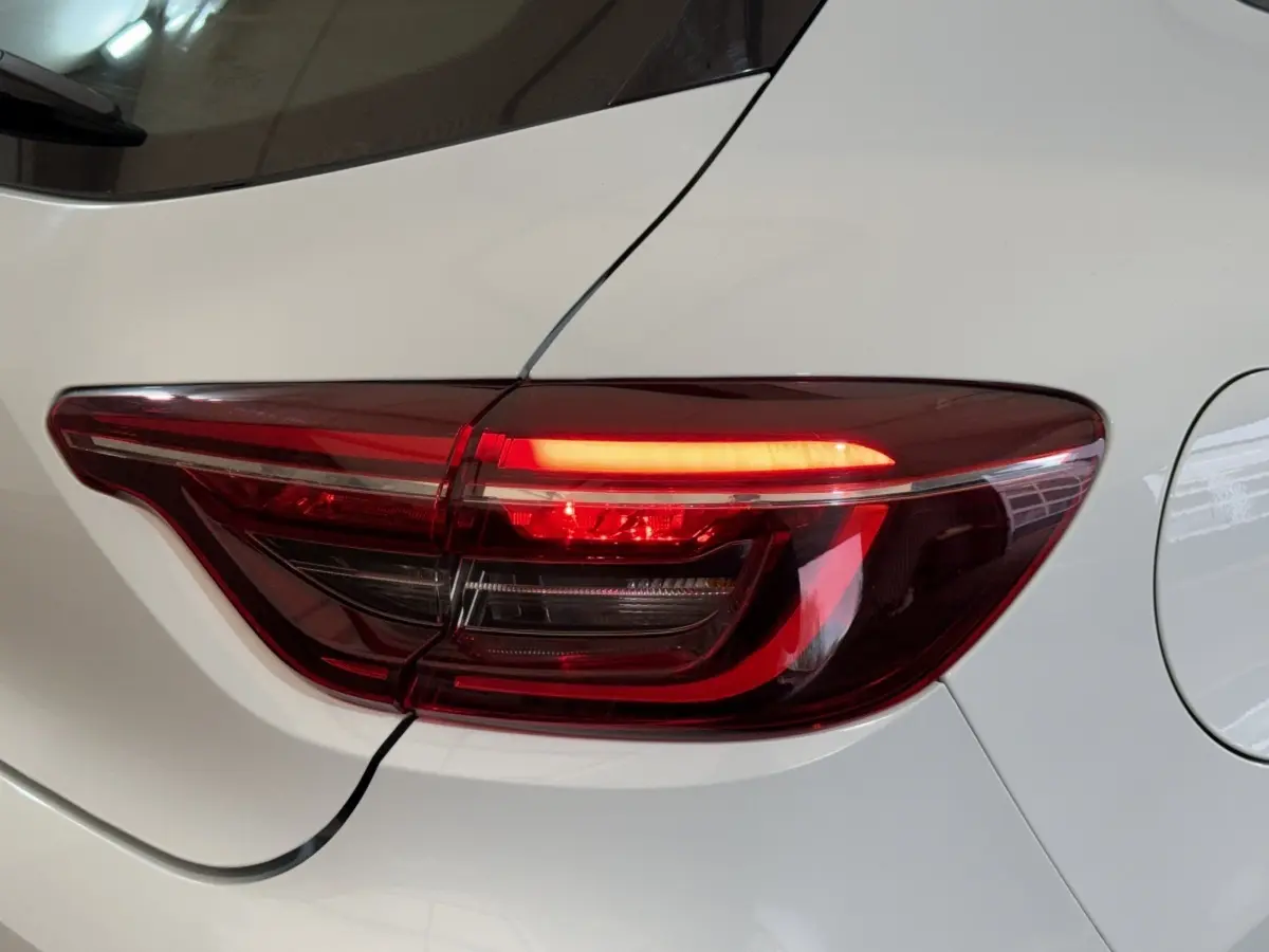 Gros plan sur le feu arrière droit rouge d'une Renault Clio Business blanche, avec la carrosserie visible autour.