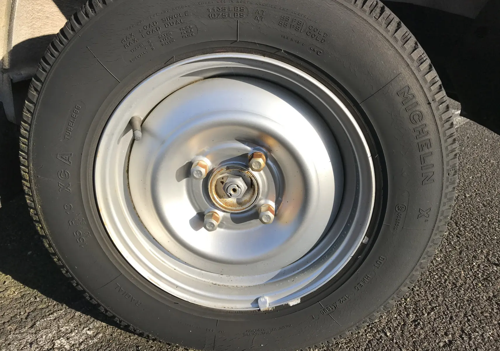 Gros plan sur la roue avant droite du Citroën C15 Isotherm blanc de 1997 avec jante acier et pneu Michelin.