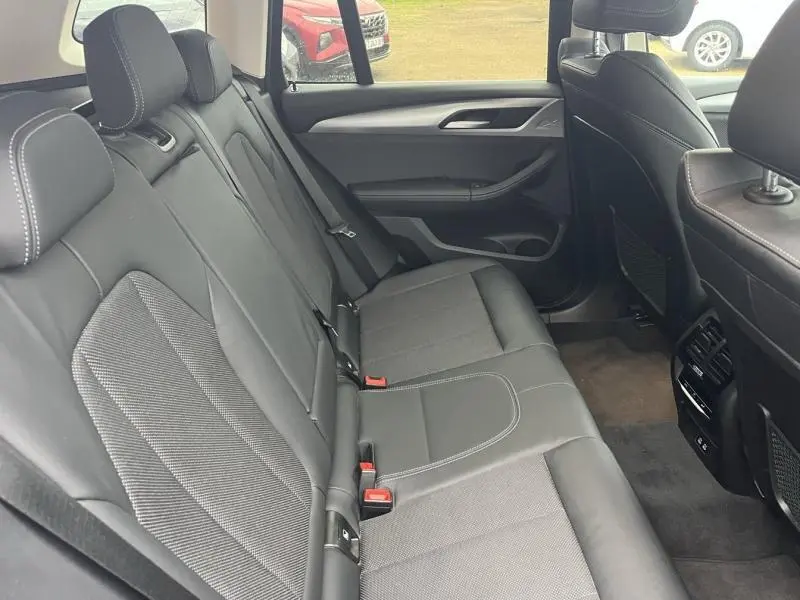 Vue intérieure de la banquette arrière noire avec surpiqûres blanches du BMW X3 xDrive30e 2020, côté droit.