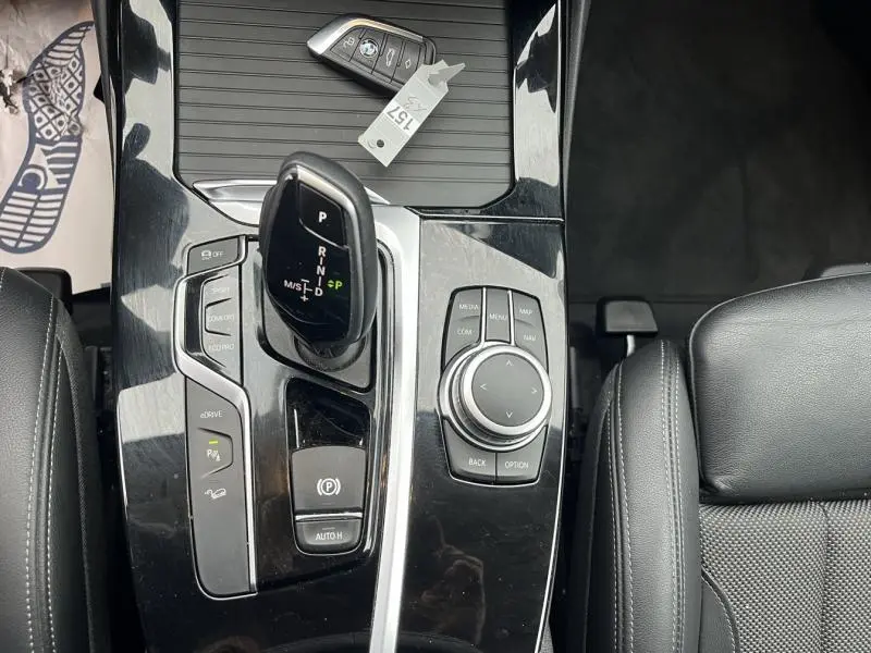 Vue plongeante sur la console centrale noire brillante du BMW X3 xDrive30e 2020, avec levier de vitesses et commandes multimédia.