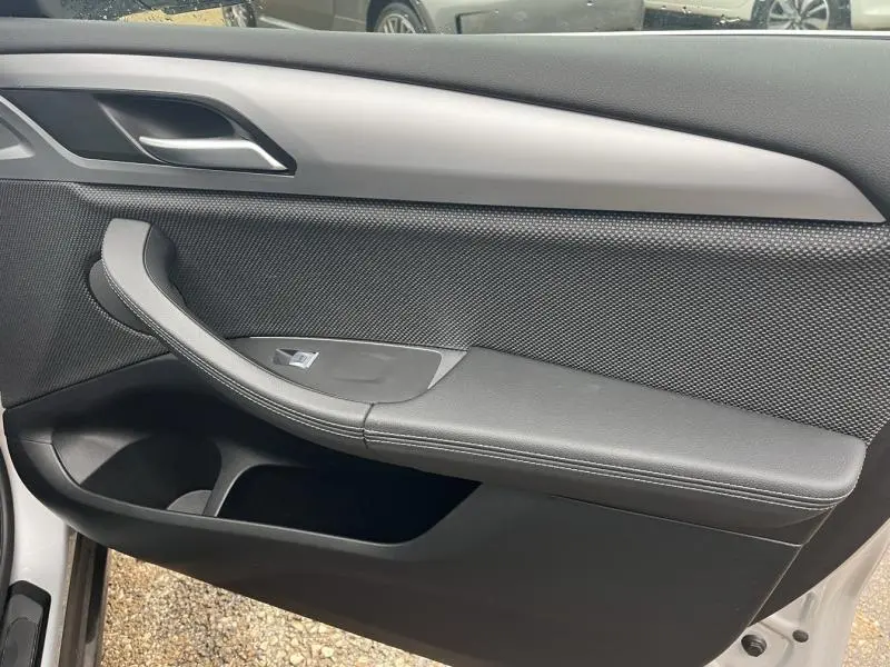 Vue rapprochée de la porte avant gauche intérieure noire d'une BMW X3 xDrive30eA Glacier Silver 2020.
