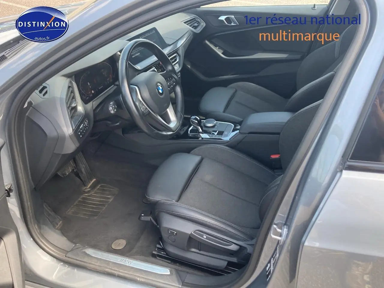 Vue intérieure côté conducteur d'une BMW Série 1 gris foncé (f40) avec sièges sport en tissu et volant multifonction cuir.