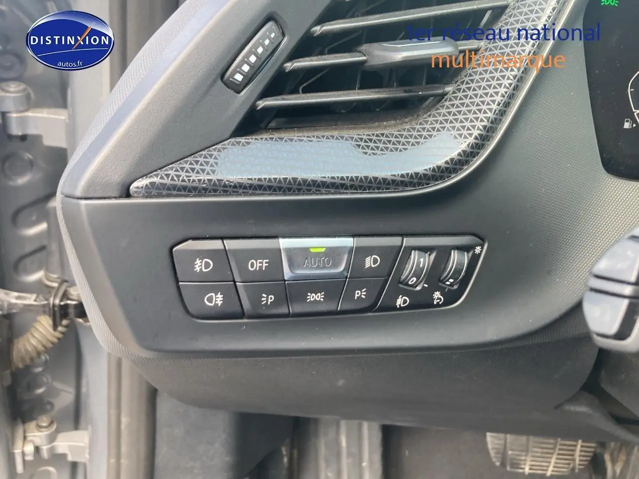 Détail des commandes d'éclairage sur la gauche du tableau de bord d'une BMW Série 1 gris foncé 2023.