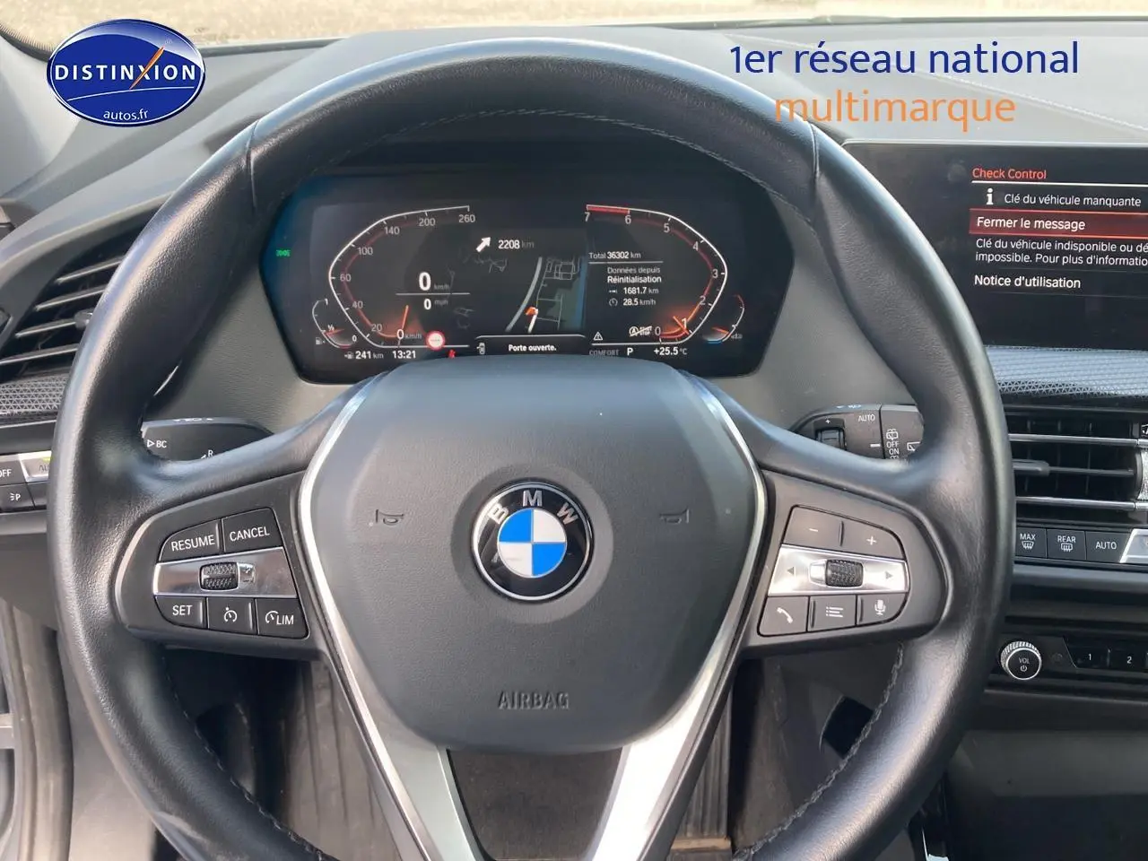 Vue rapprochée du volant cuir noir multifonction de la BMW Série 1 118i 2023 avec tableau de bord digital allumé.