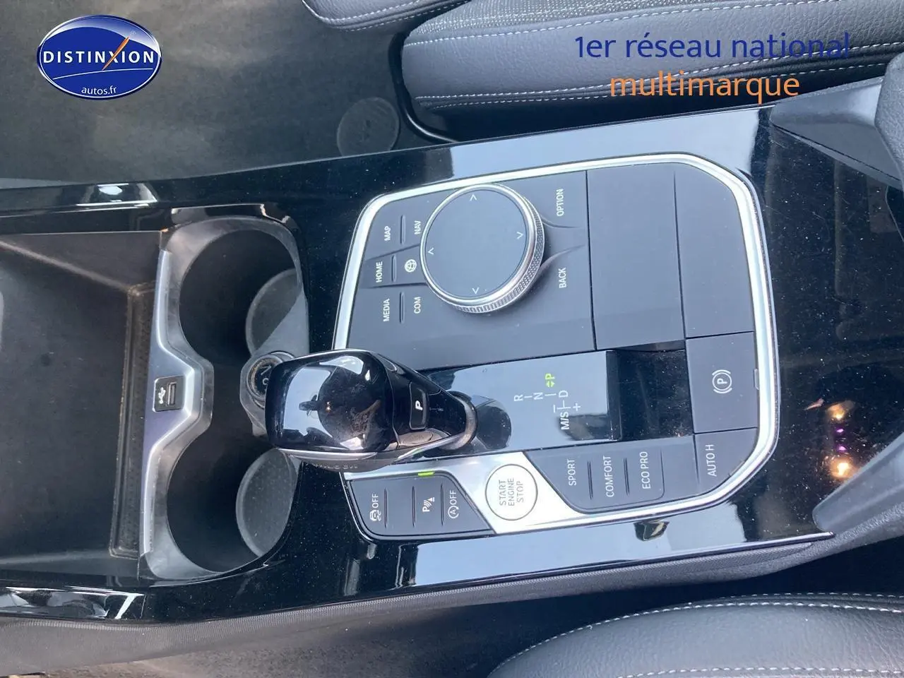 Gros plan sur la console centrale noire brillante de la BMW Série 1 118i 2023 avec levier de vitesse et commandes.