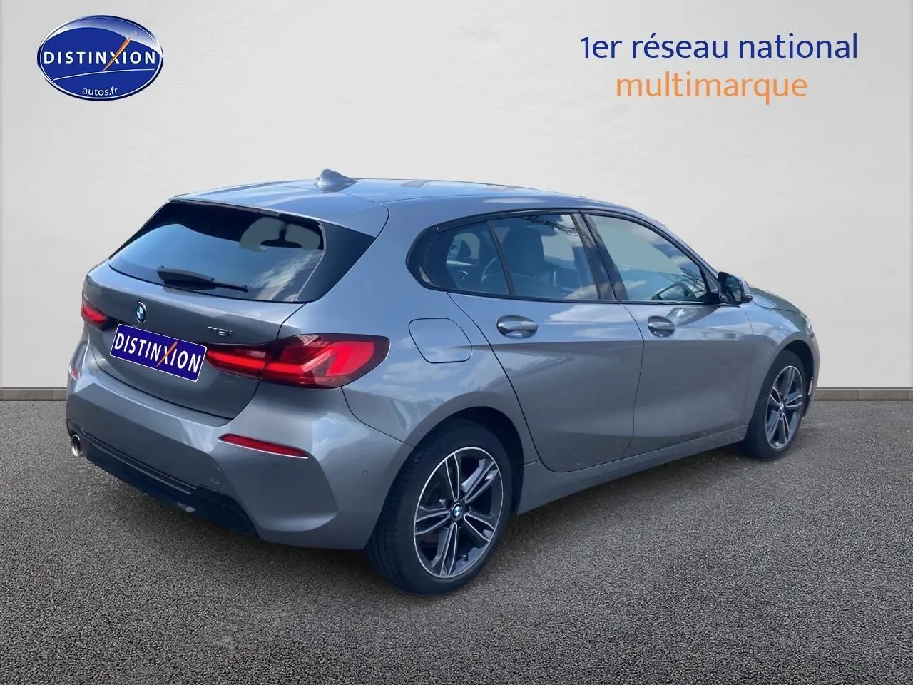 BMW Série 1 gris foncé vue 3/4 arrière droit avec jantes alliage et feux LED distinctifs.