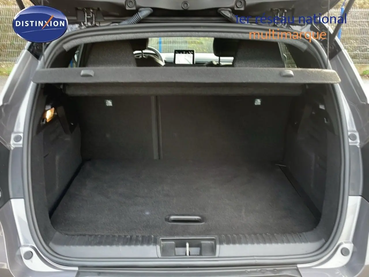 Vue arrière du coffre ouvert du Renault Captur gris Cassiopée métal avec toit noir, montrant un espace de rangement vide et propre.