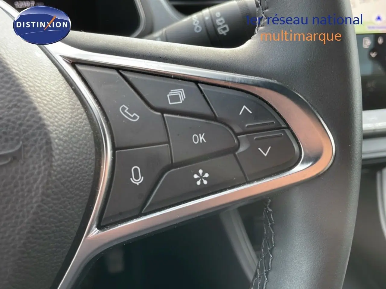 Gros plan sur les commandes multifonctions du volant noir du Renault Captur 2025, finition gris Cassiopée métal.