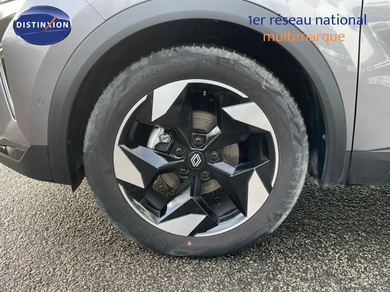 Gros plan sur la roue avant gauche du Renault Captur gris Cassiopée métal avec jante noire et argentée au design géométrique.