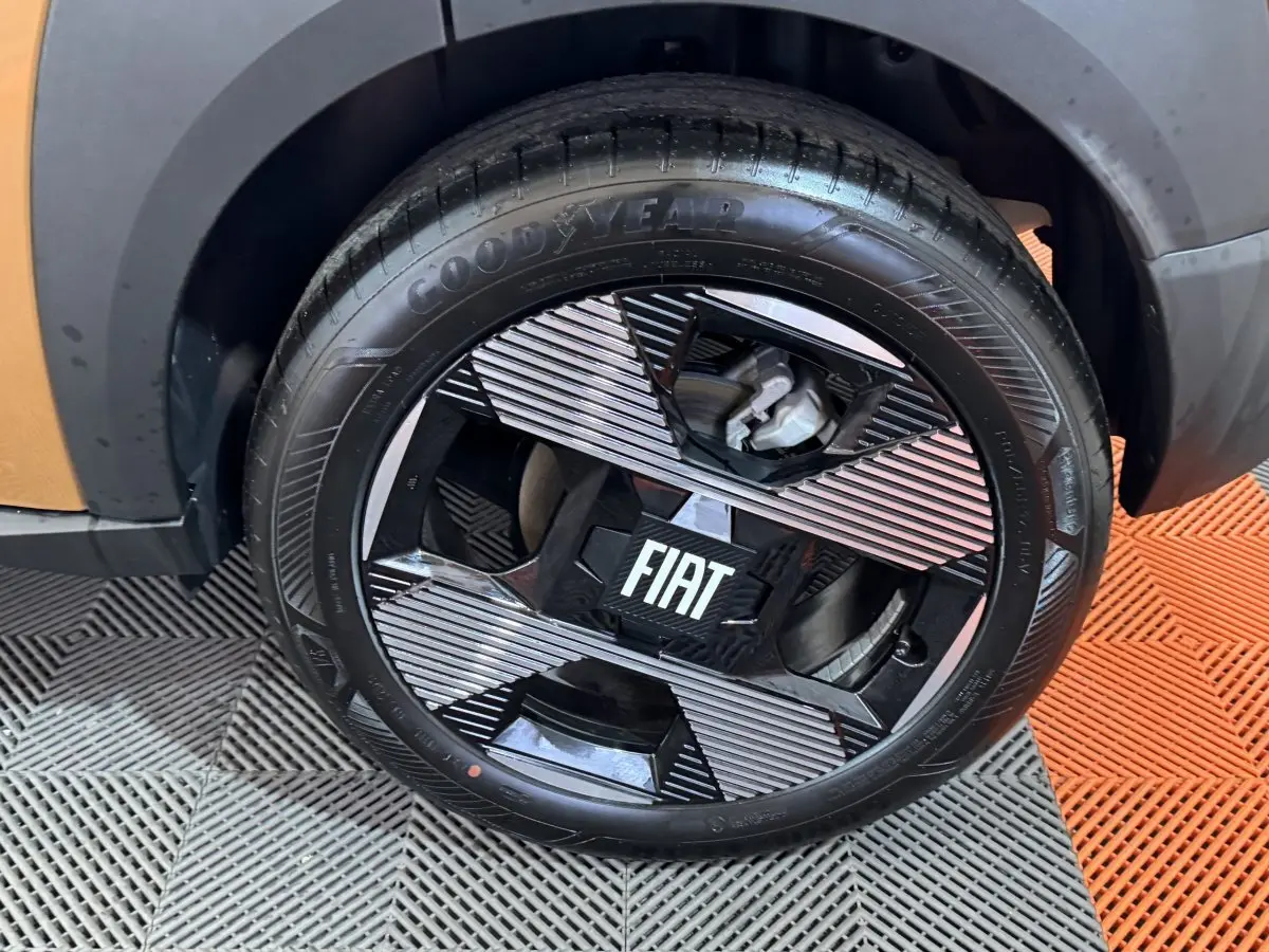 Gros plan sur la roue avant gauche marron du FIAT Grande Panda 1.2 Hybrid avec jante noire et détails argentés.