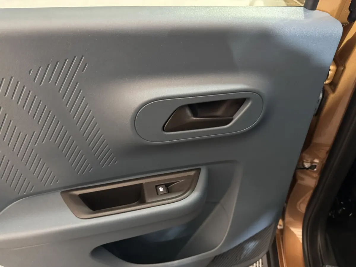 Vue rapprochée de la porte intérieure côté droit de la Fiat Grande Panda marron avec poignée et bouton de verrouillage.