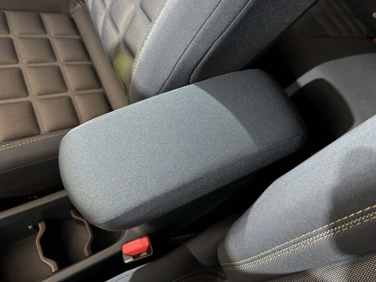 Accoudoir central gris foncé et sièges tissu marron avec surpiqûres jaunes dans une Fiat Grande Panda 2025.