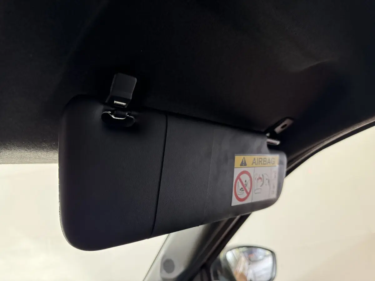 Détail du pare-soleil côté conducteur avec étiquette airbag, rétro électrique visible sur une FIAT Grande Panda marron.
