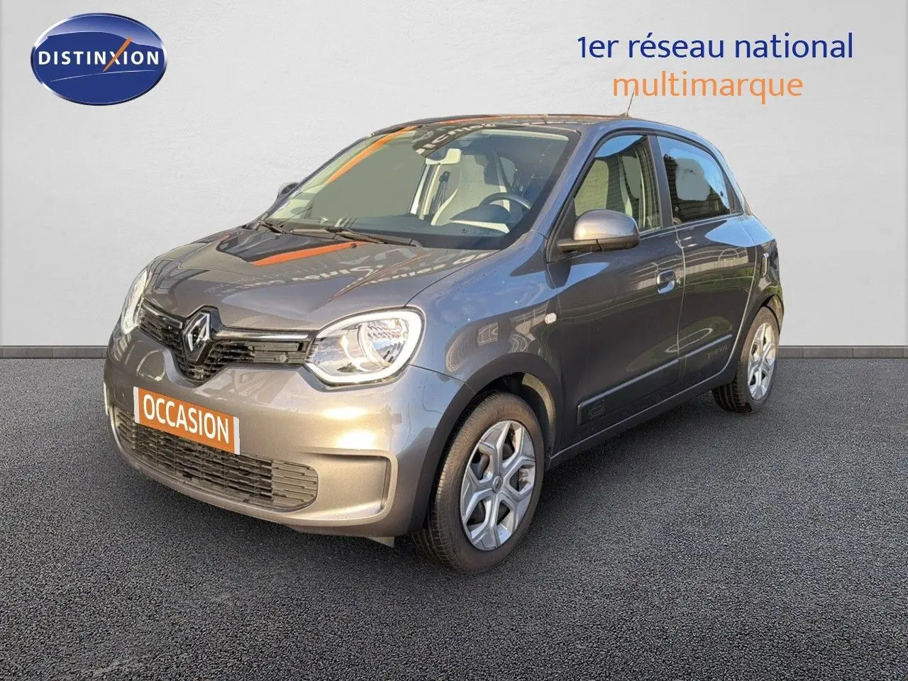 Renault Twingo gris acier vue 3/4 avant droit, compacte cinq portes avec phares arrondis et jantes acier.