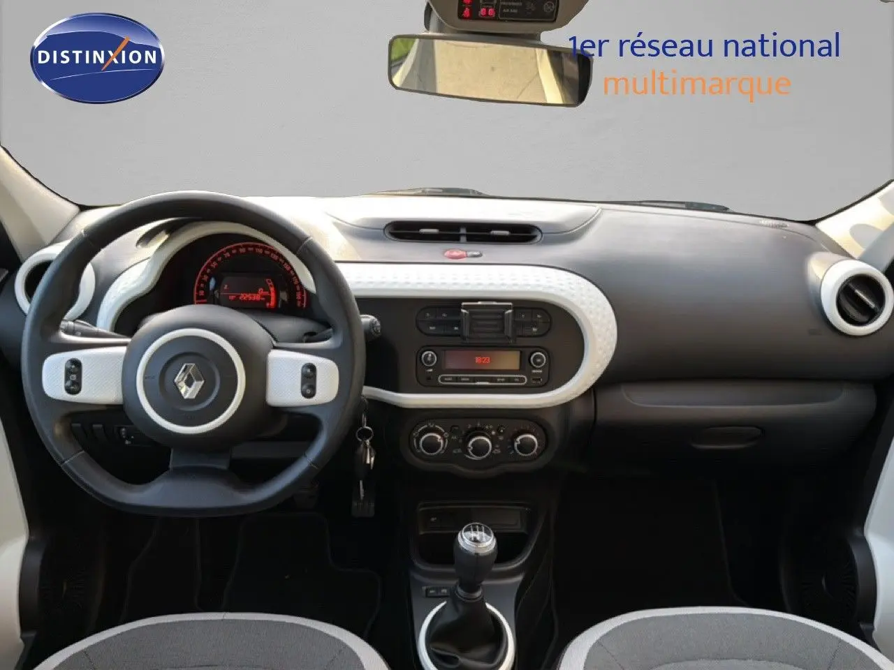 Vue intérieure avant du tableau de bord gris et noir de la Renault Twingo 1.0 SCE 65 Zen avec volant multifonction et levier de vitesse manuel.