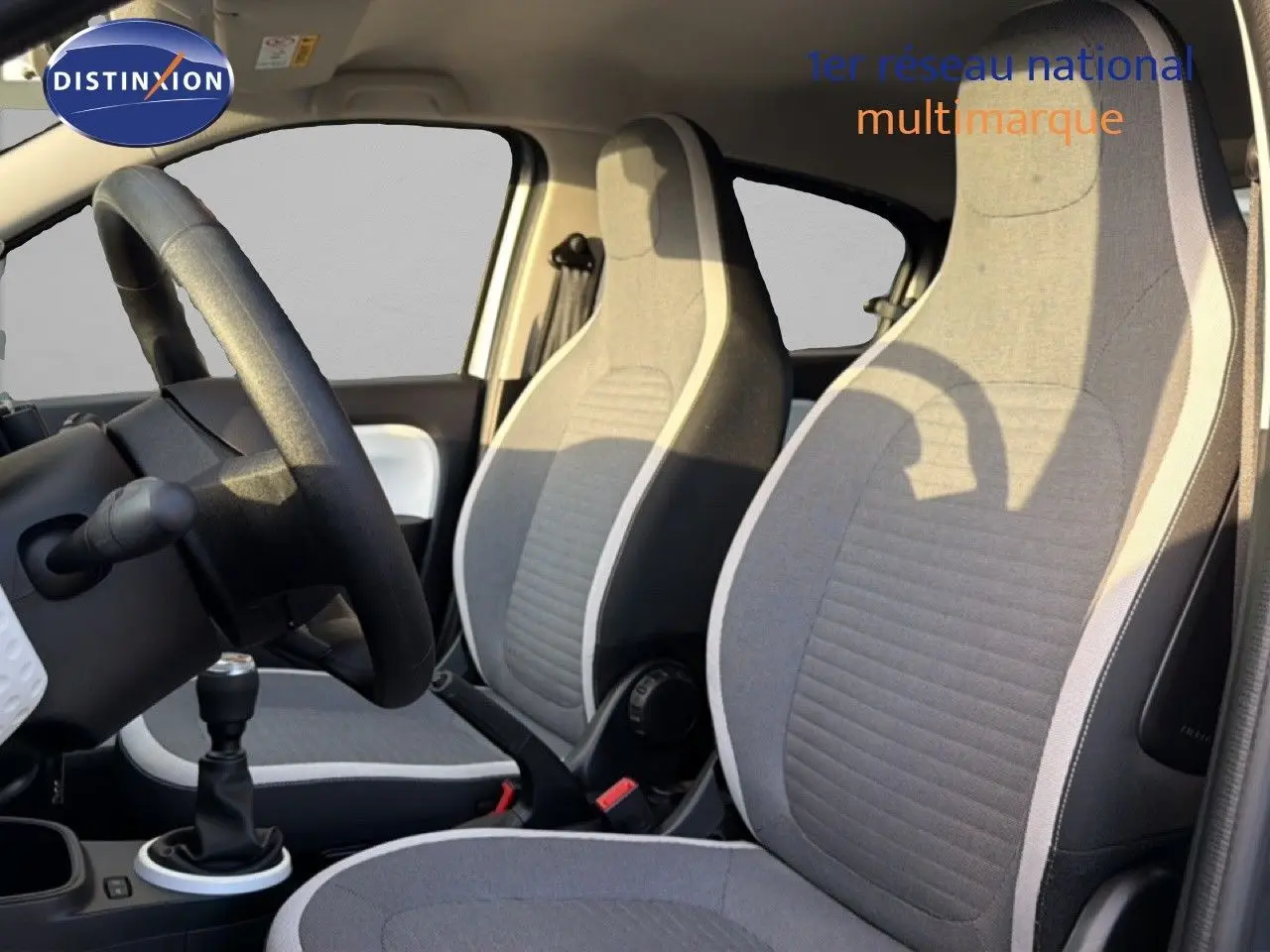 Vue intérieure côté conducteur de la Renault Twingo gris acier 2021, sièges tissu gris avec surpiqûres claires.