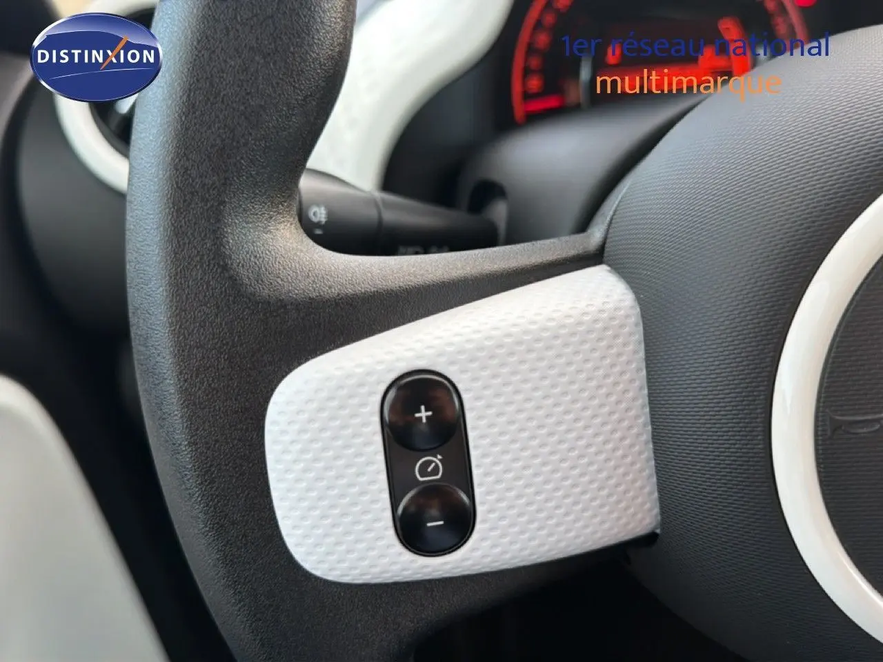 Gros plan sur les commandes de régulateur de vitesse sur le volant noir et gris acier d’une Renault Twingo 1.0 SCE 65 Zen.
