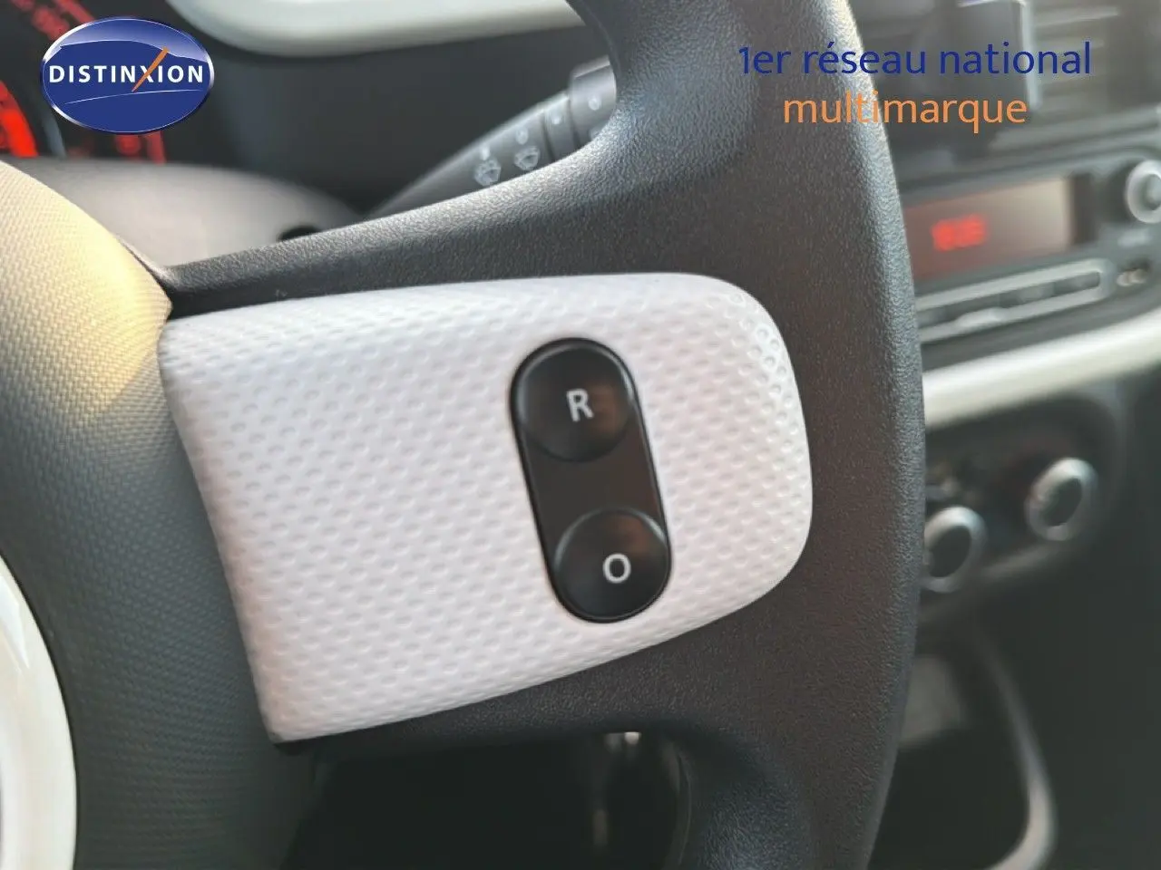 Gros plan sur le volant noir et blanc texturé de la Renault Twingo gris acier, avec boutons de commande visibles.