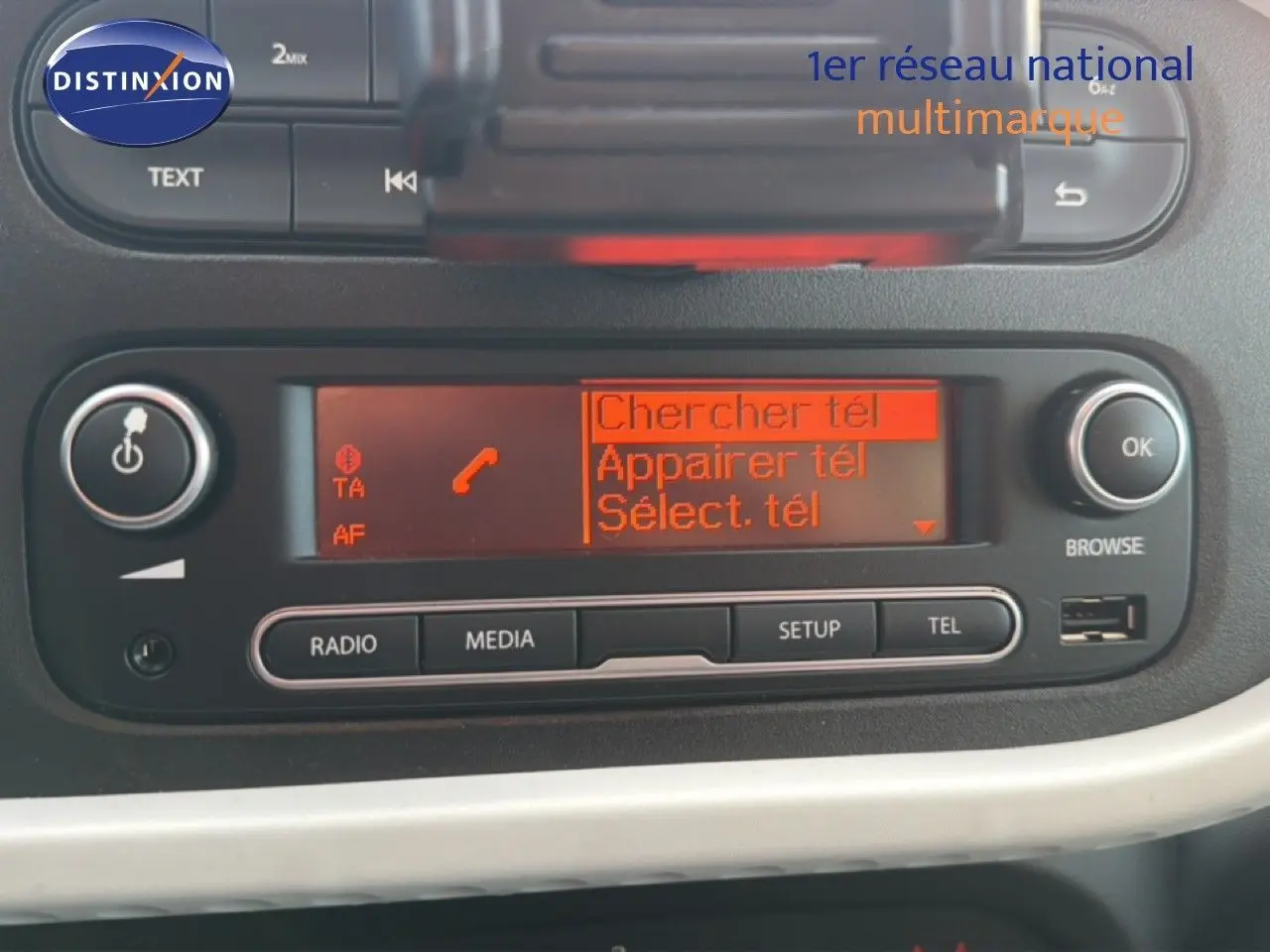 Détail de l'autoradio avec écran orange affichant les options de connexion téléphone dans une Renault Twingo gris acier.