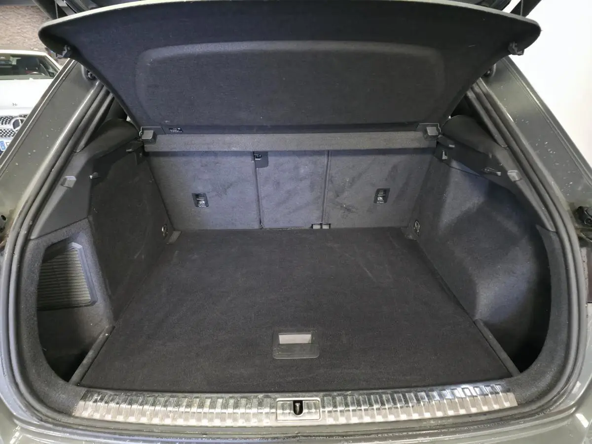Coffre ouvert d’un Audi Q3 gris, vue arrière montrant l’espace de chargement et la finition intérieure noire.