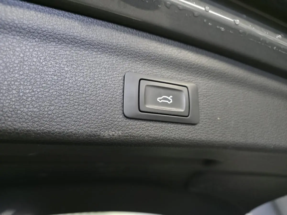 Bouton d'ouverture électrique du hayon sur la garniture intérieure du coffre gris d'un Audi Q3 S Line hybride rechargeable.