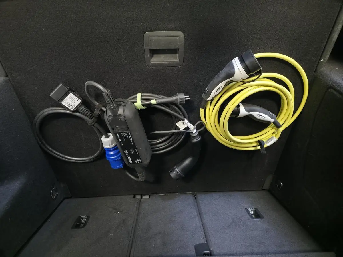 Coffre arrière d’Audi Q3 gris avec câbles de recharge hybride bien rangés sur la paroi intérieure.