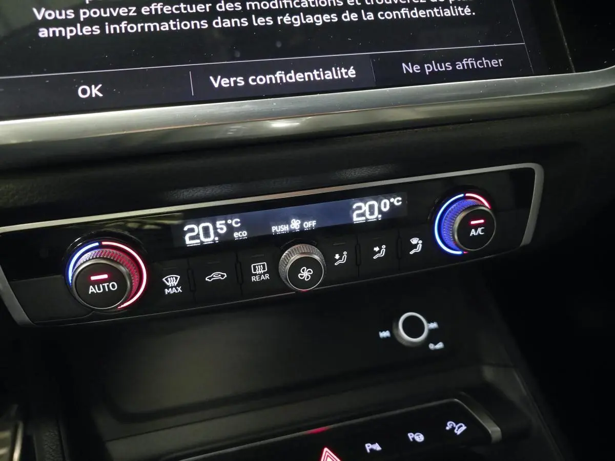 Détail de la console centrale de l’Audi Q3 S Line 2021 montrant la climatisation automatique bi-zone avec réglages numériques.