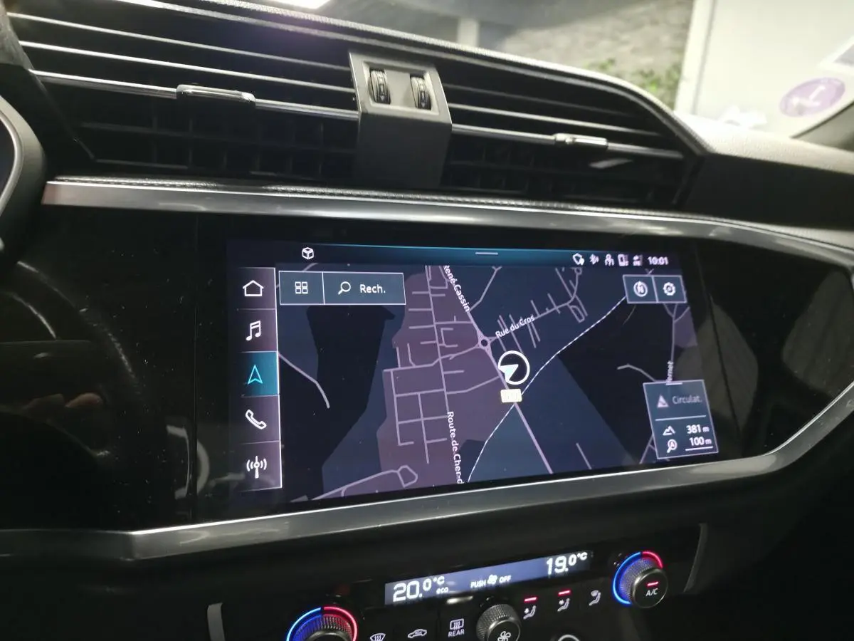 Écran tactile central affichant la navigation dans l’Audi Q3 S Line, intérieur noir avec commandes climatisation digitales.