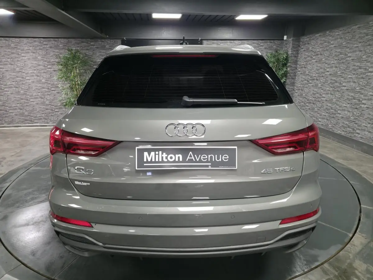 Vue arrière d'un Audi Q3 gris hybride rechargeable 45 TFSI e avec feux LED et vitres arrière surteintées.