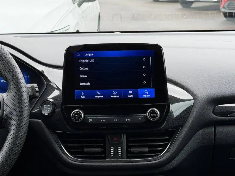 Vue intérieure centrée sur l'écran tactile multifonction du Ford Puma 2024 gris Solar avec commandes audio et bouton start/stop.