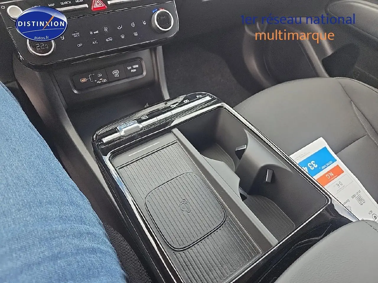 Gros plan sur la console centrale noire du Hyundai Tucson 2025 avec chargeur sans fil et porte-gobelets visibles.