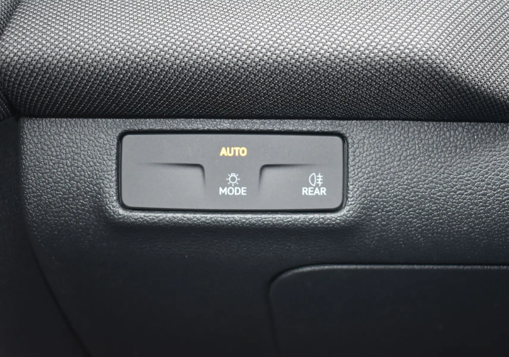 Détail du tableau de bord noir avec commande d'éclairage automatique et feux arrière sur Volkswagen T-Roc blanc.