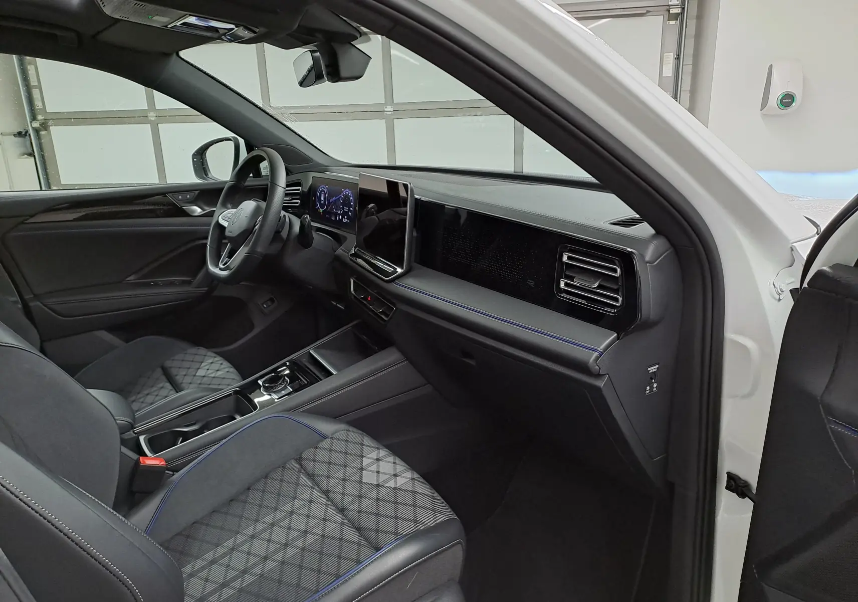 Intérieur du Volkswagen Tiguan 2025 blanc pur, vue côté passager, tableau de bord moderne avec écran tactile central.