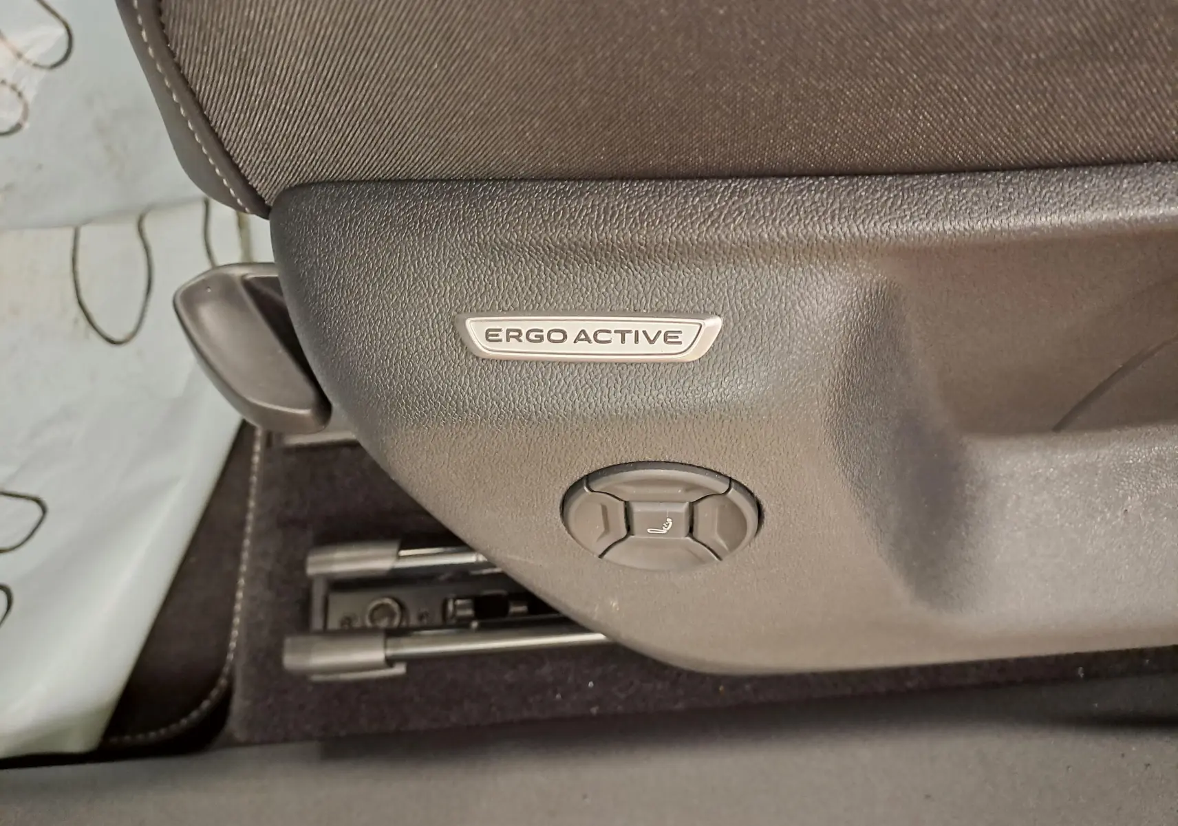 Détail du réglage de siège Ergo Active en plastique noir dans l'habitacle du Volkswagen Tiguan blanc.