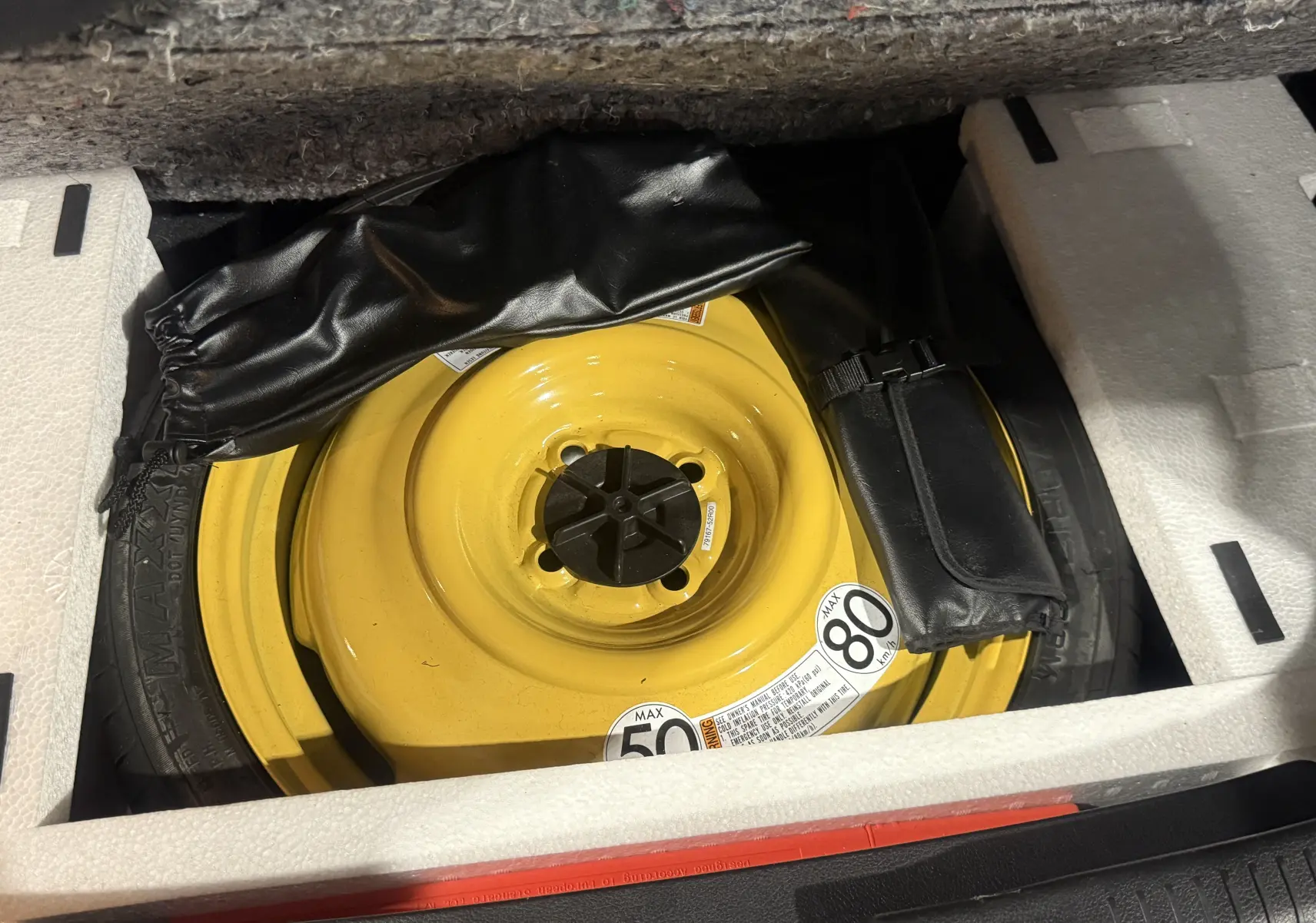 Roue de secours jaune en gros plan dans le coffre d'une Suzuki Ignis orange 2022, version hybride Allgrip.