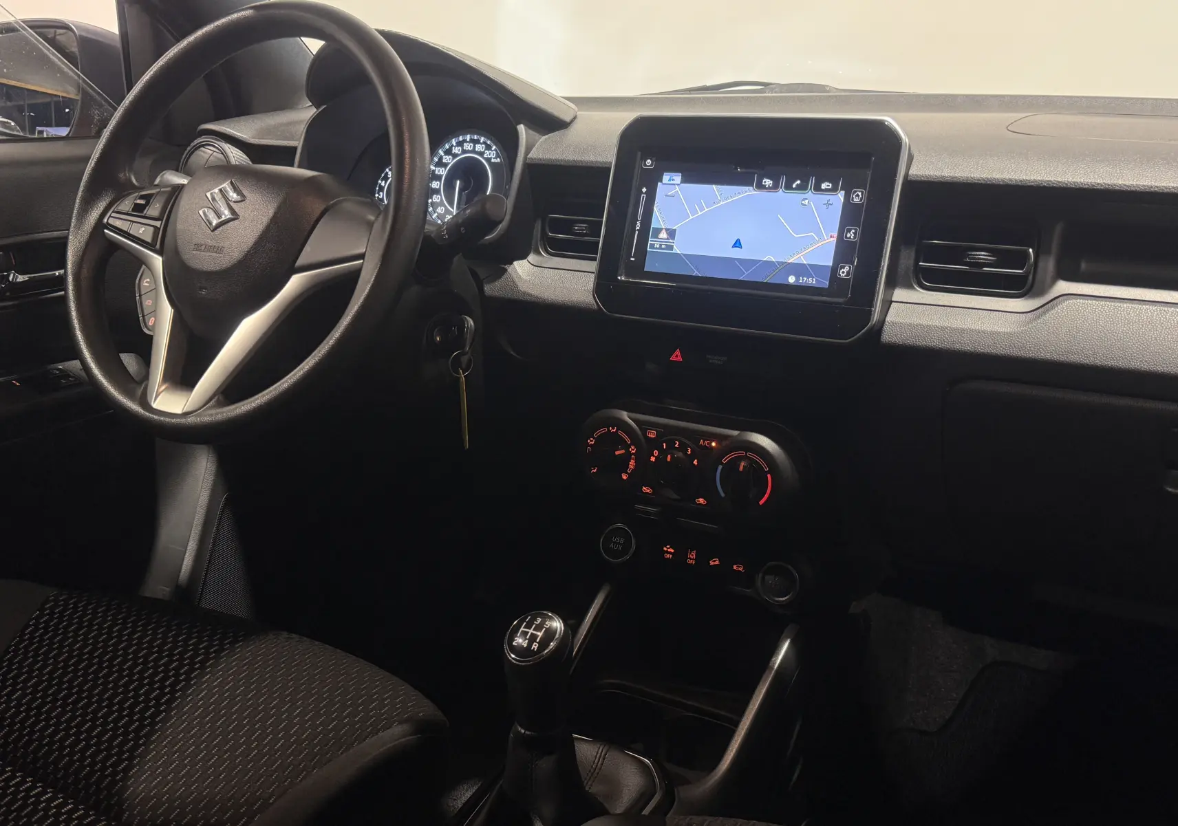 Vue intérieure de face du tableau de bord de la Suzuki Ignis 2022, avec écran tactile et levier de vitesse manuel.